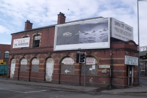 Ein Designer-Showroom-Gebäude mit Plakaten an der Fassade und dem Bürgersteig, ein Verkehrszeichenmast auf dem Gehweg und ein Himmel mit Wolken im Hintergrund.