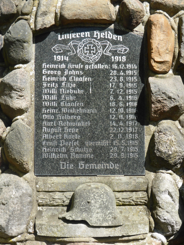 Steinwand mit einer Gedenktafel mit Text und einem Helm darauf, der wahrscheinlich den deutschen Militärdienst im Zweiten Weltkrieg ehrt.