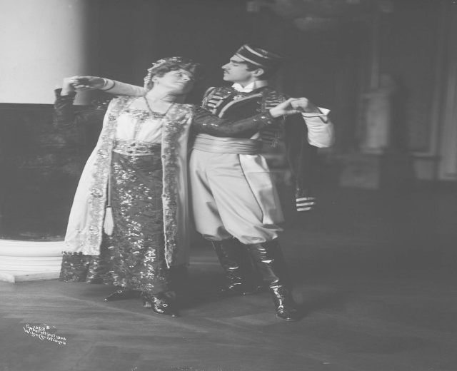 Schwarz-weiß-Foto eines Mannes und einer Frau, die in einem Ballsaal tanzen, mit einer Säule und einer Wand im Hintergrund; der Mann trägt Schuhe, was darauf hinweist, dass sie performen.