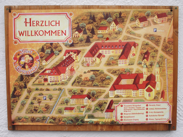 A detailed map of Herzlich Willkommen, Germany, mounted on a building wall, showing streets, buildings, and landmarks, with additional text about the town's history, culture, and attractions.