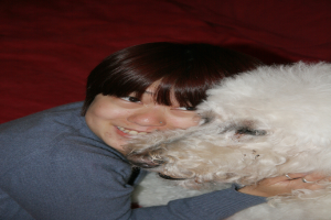 Eine Frau lächelt, während sie ein Haustier in den Armen hält.