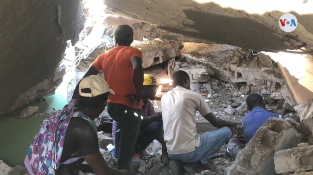 Menschen sitzen auf Trümmern nach einem Gebäudeeinsturz in Lagos, Nigeria, und suchen nach Überlebenden.