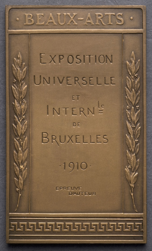 Bronzeplatte mit der Inschrift "Exposition Universelle et Internationale de Bruxelles 1910" in fetter Schrift, umgeben von einem dekorativen Rahmen, mit einem Glanzfinish.