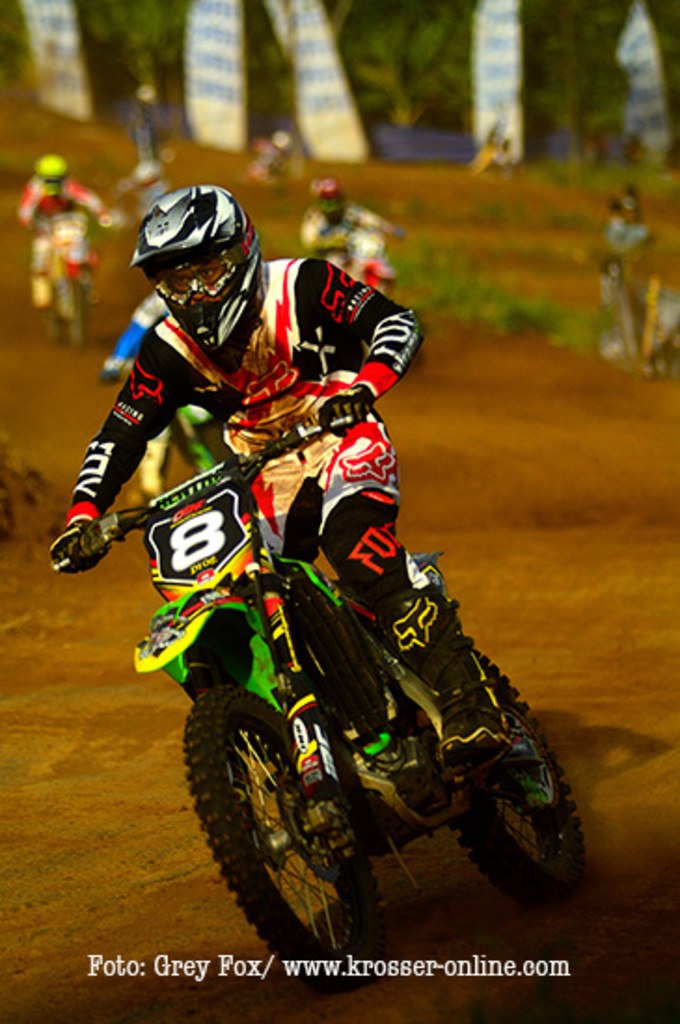 A group of motorcyclists racing on a track, wearing helmets, with text visible at the bottom.