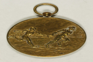 Goldmedaille mit zwei laufenden Männern darauf vor einem weißen Hintergrund.