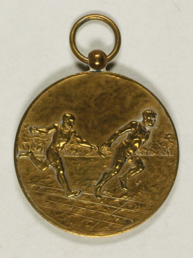 Goldmedaille mit zwei laufenden Männern darauf vor einem weißen Hintergrund.