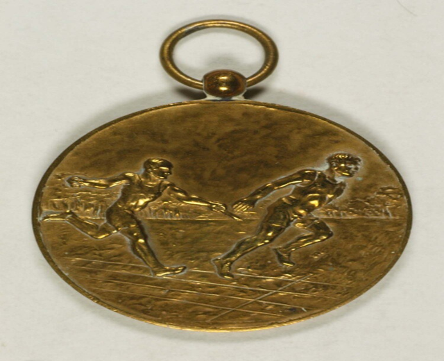 Goldmedaille mit zwei laufenden Männern darauf vor einem weißen Hintergrund.