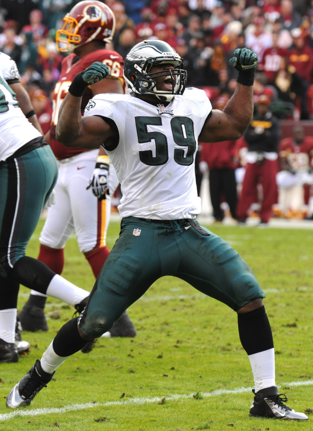 Philadelphia Eagles running back Michael Vick in a green and white uniform celebrates a touchdown, helmet and gloves visible, surrounded by teammates and opponents on the field.