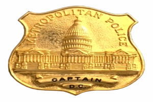 Ein goldenes Polizeibadgen mit der Inschrift "Metropolitan Police Captain" auf einem weißen Hintergrund.