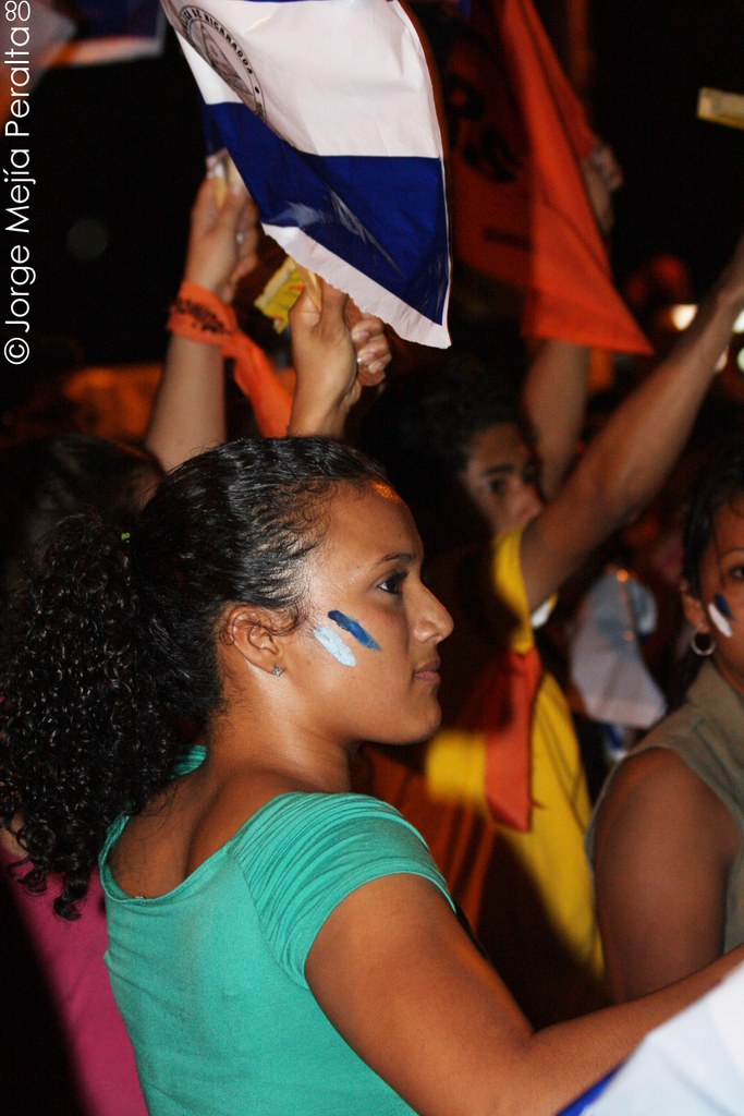 Frauen in grünen T-Shirts, die auf einer Demonstration stehen und weiße Decken halten.