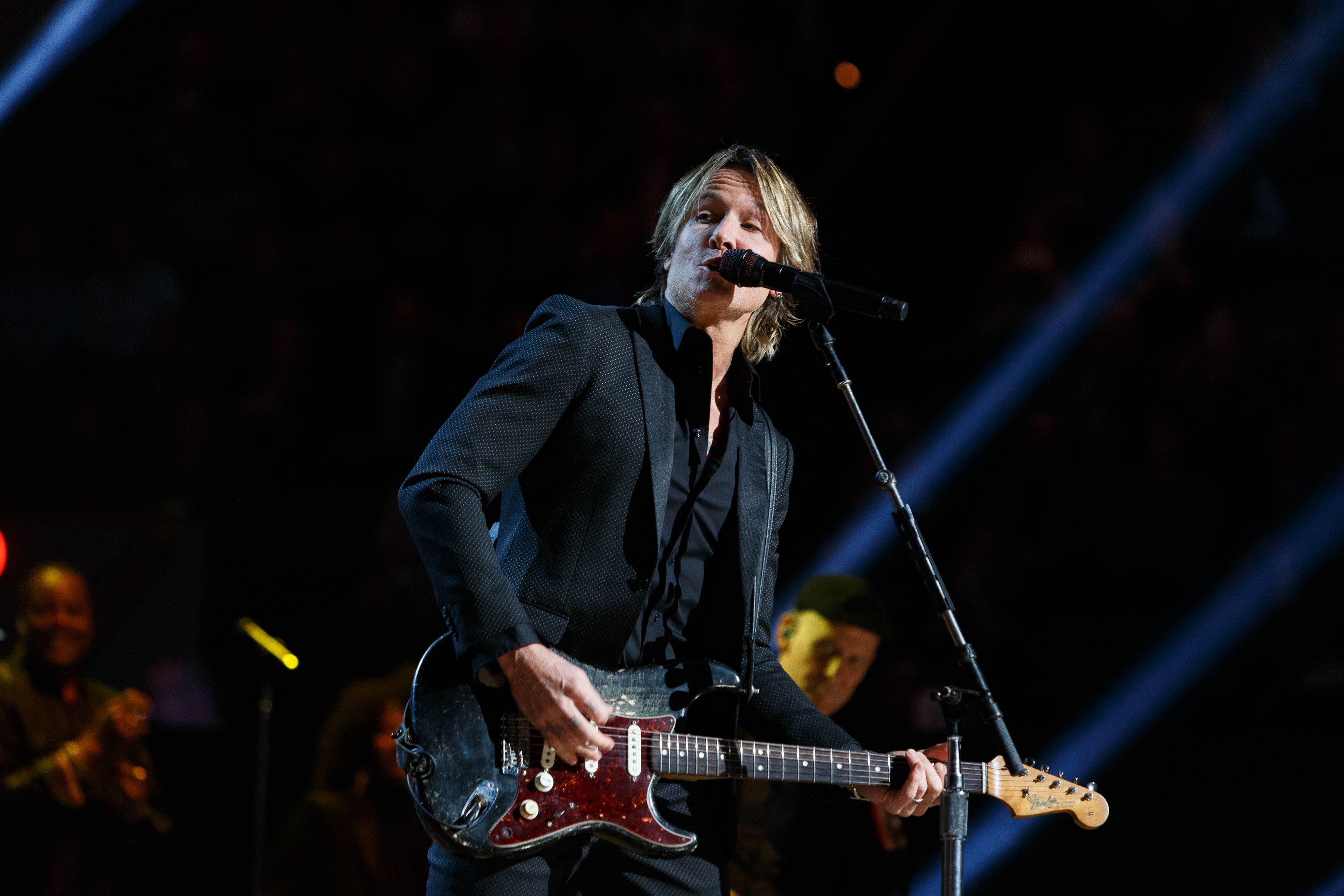 Keith Urban performs auf der Bühne im Joint in Las Vegas, spielt eine Gitarre mit einem Mikrofon davor und Musiker im Hintergrund, bei dunkler Beleuchtung.