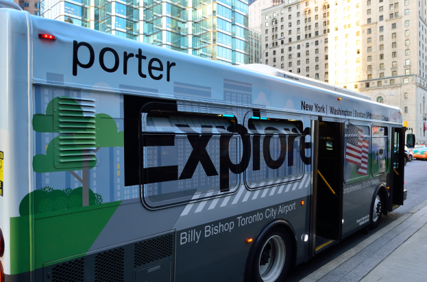 Ein Expressbus der Porter-Express steht auf der Seite einer Stadtstraße, umgeben von hohen Gebäuden und einem Fußweg auf der rechten Seite.