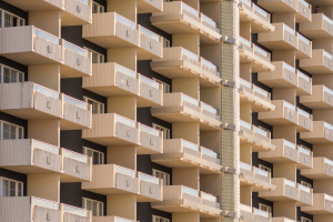Ein hoher Wohnblock mit mehreren Ebenen, jede mit Glasbalkonen und Geländern.