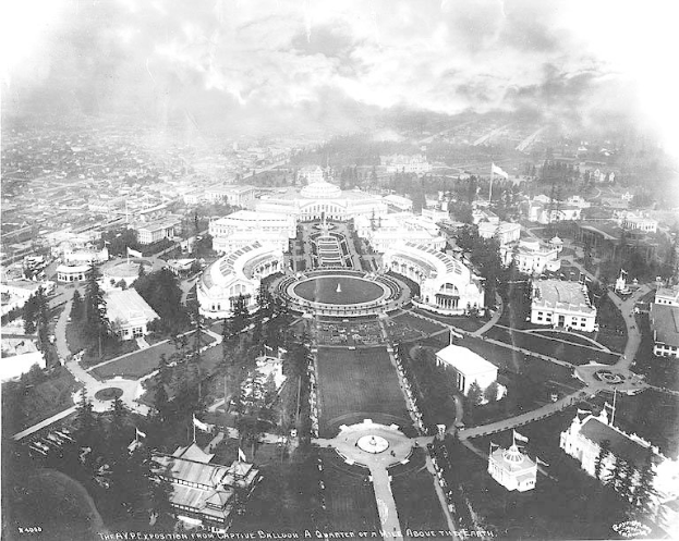 Aerial black and white view of the White House in Washington, D.C., showing surrounding buildings, trees, roads, vehicles, and a central fountain.