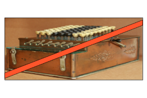 Eine altmodische Kasse mit einem roten Kreuz darüber, mit einigen Knöpfen und einem roten Band, auf einem Tisch.