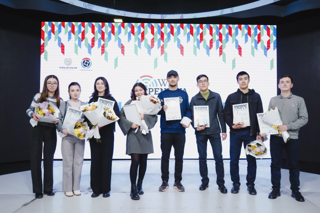 A group of people on a stage holding bouquets and certificates, with a screen displaying "Yogyakarta Penang International School" in the background.