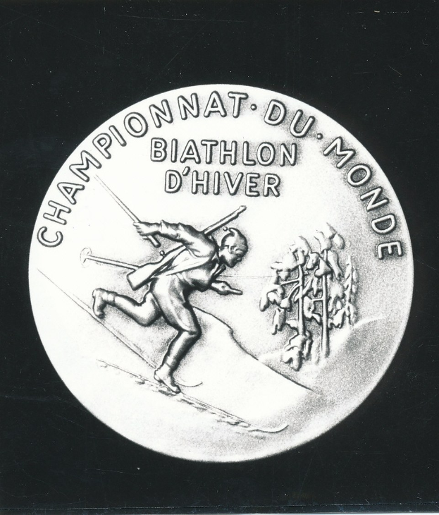 Silberne Medaille mit einem Skifahrer, mit eingravierter Schrift, auf schwarzem Hintergrund.