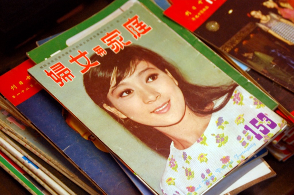 Eine Sammlung von Zeitschriften auf einem Tisch, wobei die obere Zeitschrift ein Bild einer Frau zeigt.