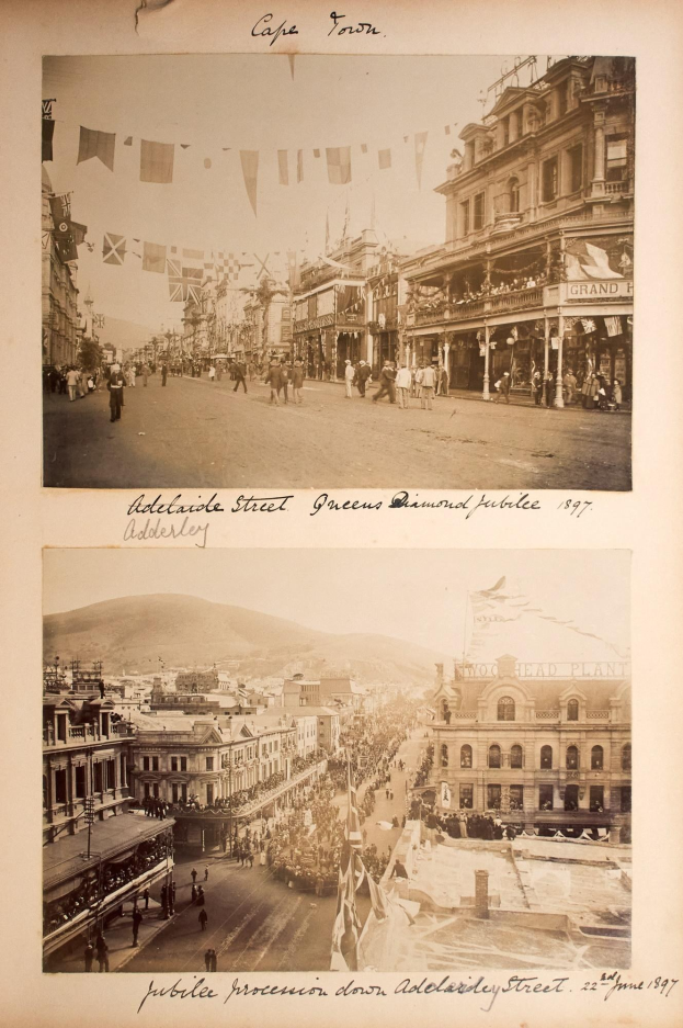 Schwarz-weißes Foto von Adelaide Street während der Diamantenen Hochzeit der Queen im Jahr 1897, das Gebäude, Menschen, Flaggen und einen Hügel im Hintergrund zeigt.
