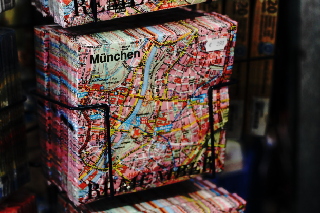 A stack of books with a map of Munich printed on them, set against a slightly blurred background.