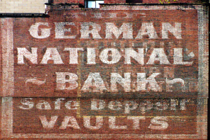 Eine Ziegelwand mit einem Schild, das "Deutsche Nationalbank Safe Deposit Vaults" und ein Fenster oben zeigt.