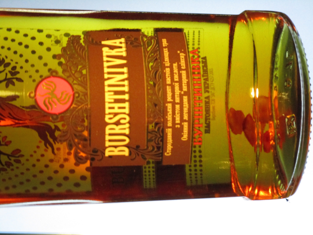 Eine Flasche Olivenöl mit einer goldbraunen Flüssigkeit steht auf einem Tisch und zeigt ein Etikett.