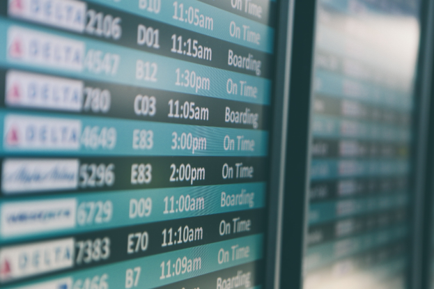 Nahaufnahme eines Flughafen-Abflugtafels mit Fluginformationen und verpixelten Hintergrund.