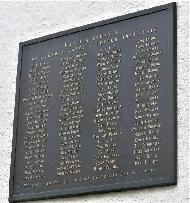 Plaque mounted on a building's wall with the inscription "Plaque for the victims of the Holocaust" in bold font, surrounded by a decorative border.