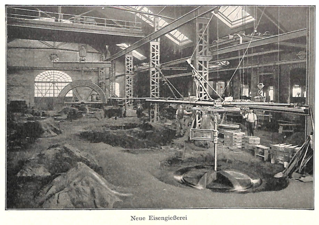 Schwarzes und weißes Foto einer Fabrik mit Arbeitern, die an Maschinen arbeiten, umgeben von Metallstangen und -pfählen, beschriftet mit "Neue Eisenglebeerei, die erste Fabrik in Deutschland".