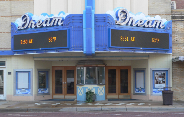 Außenansicht des Dream Theaters in St. Louis, Missouri, mit Glastüren und -fenstern, einer Schautafel, einem Müllbehälter, einem Topf mit einer Pflanze und einer Straße unten.