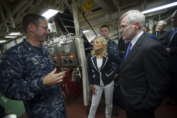 Eine Gruppe von Menschen in einem Raum mit Industrieausrüstung, mit einem Befehlshaber in der Mitte des Gesprächs.
