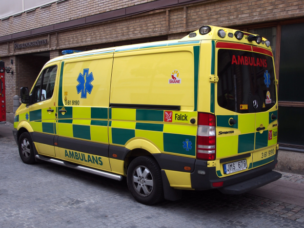 Rettungswagen auf der Straße vor einem Backsteinbau mit Text geparkt, mit einem Feuerlöscher auf der linken Seite sichtbar.