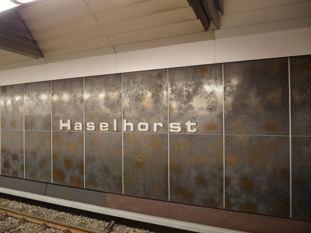 A train station sign reading "Haselhorst" illuminated on a wall in Berlin, Germany.