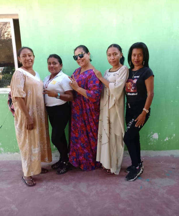 Eine Gruppe von Frauen, die vor einer grünen Wand mit einem Fenster auf der linken Seite stehen und an einem Internationalen Frauentag-Event teilnehmen.