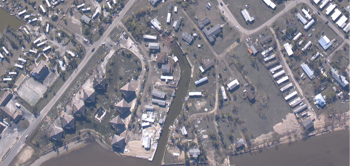 Aerial view of a city with buildings, trees, roads, vehicles, and water affected by Hurricane Katrina.