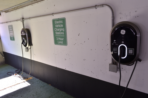 Ein Elektrofahrzeug-Ladestation in einer Tiefgarage mit zwei Ladestationen an der Wand und Tafeln mit Text darauf, der Boden ist unten im Bild zu sehen.