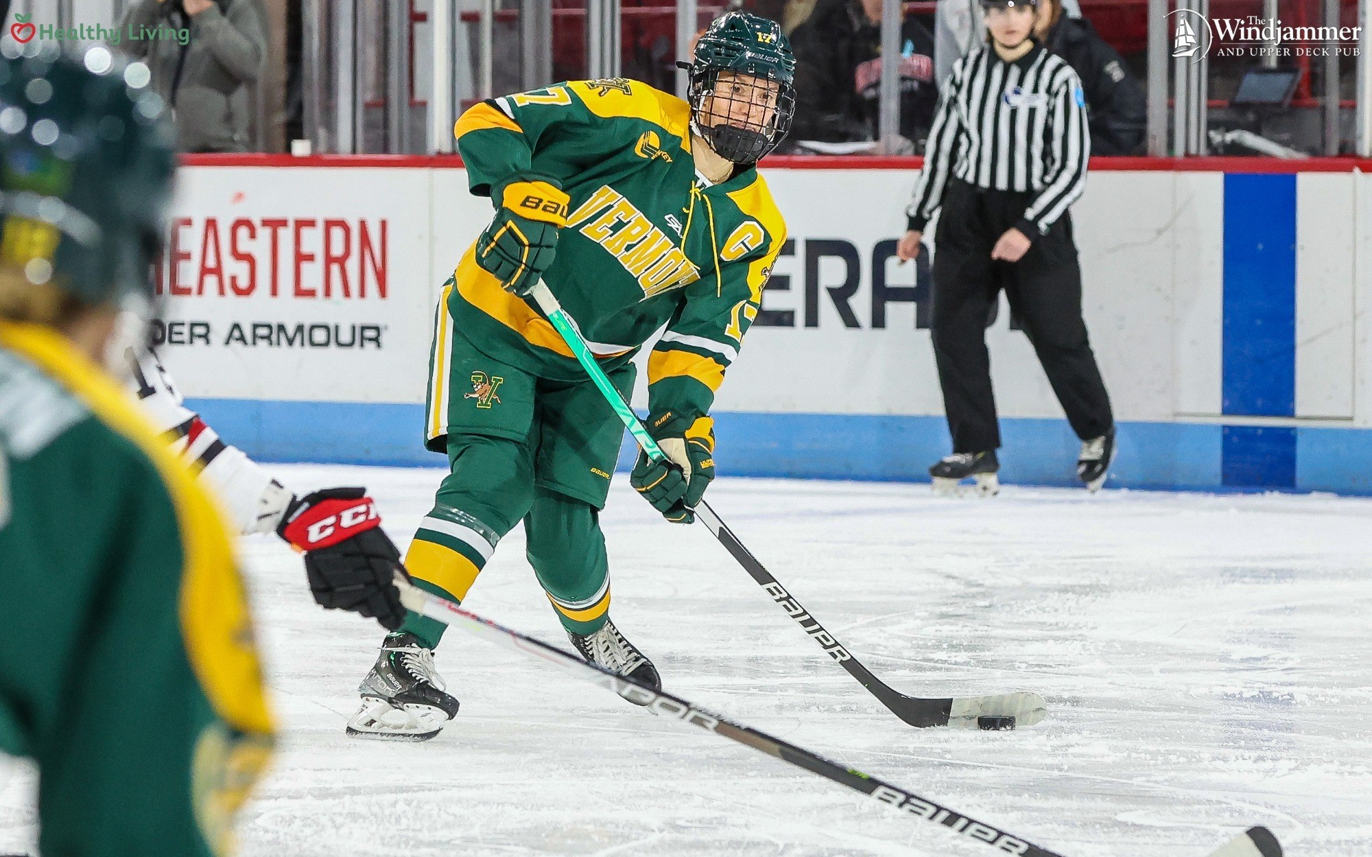 Gruppe junger Männer in Eishockey-Ausrüstung beim Spiel auf einem Eisstadion mit Zuschauern im Hintergrund.