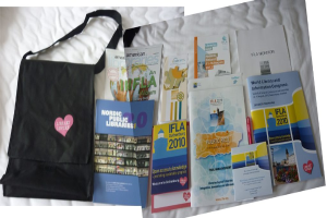 Eine Tasche mit 'Bibliothekliebhaber' darauf und einige Bücher sind auf einem Bett platziert.