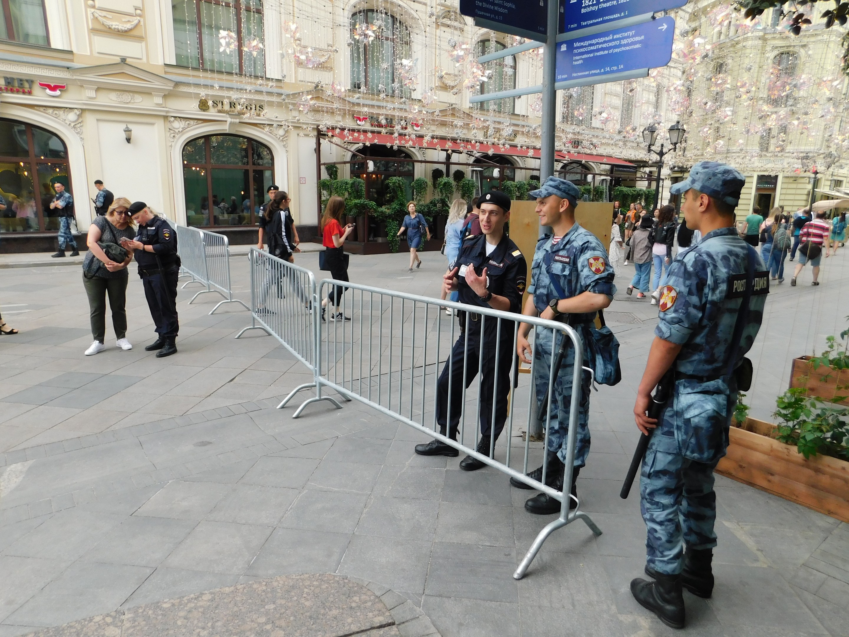 Polizeibeamte in Uniform stehen vor einer Menge, einige halten Waffen, mit Absperrungen und Schildern im Vordergrund und Gebäuden, Bäumen und Laternen im Hintergrund während eines Anti-Terror-Einsatzes in Wien, Österreich.