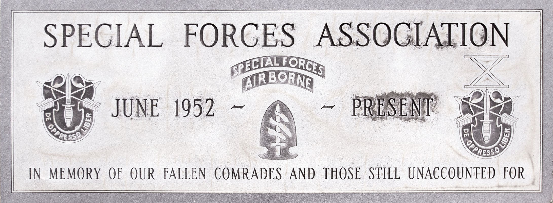 Plakette mit dem Text "Spezialeinheitenverband" und Logos der Spezialeinheitenluftlandetruppen, wahrscheinlich ein militärisches Gedenkdenkmal.