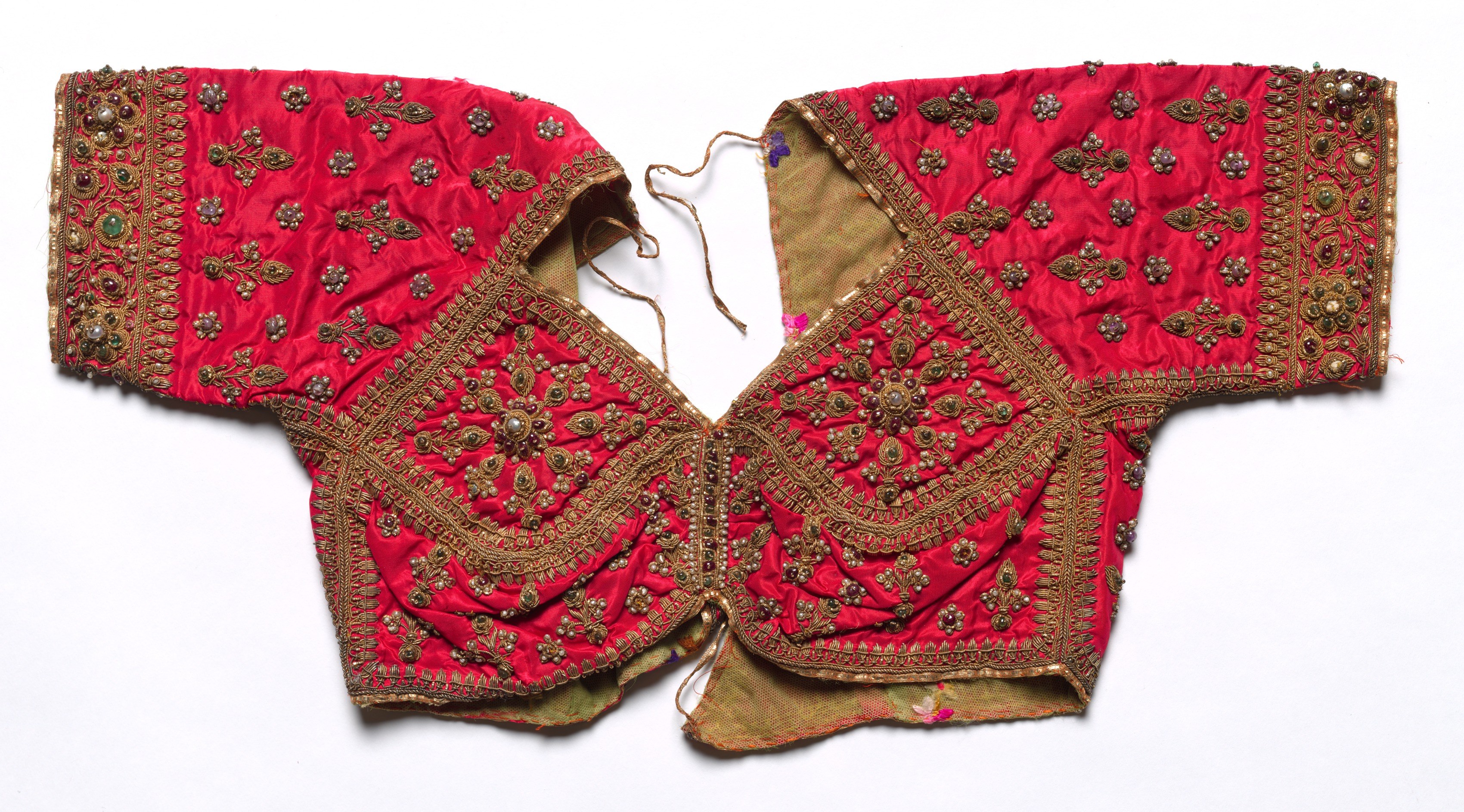 Rotes Oberteil mit goldener Stickerei, das detailreiche Muster zeigt, vor einem weißen Hintergrund.