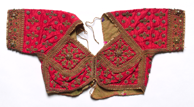 Rotes Oberteil mit goldener Stickerei, das detailreiche Muster zeigt, vor einem weißen Hintergrund.