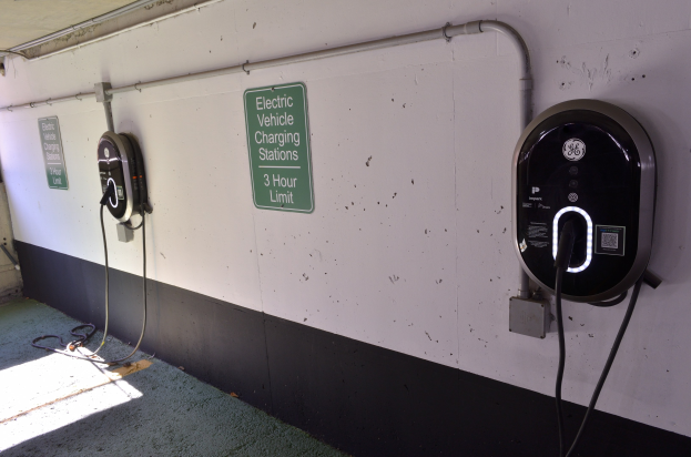 Elektrofahrzeug-Ladestation in einer Tiefgarage an der Wand montiert, mit Informationsschildern darunter.