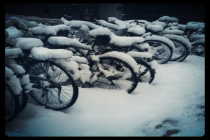 Mehrere Fahrräder stehen auf einem schneebedeckten Boden, ebenfalls mit Schnee bedeckt.