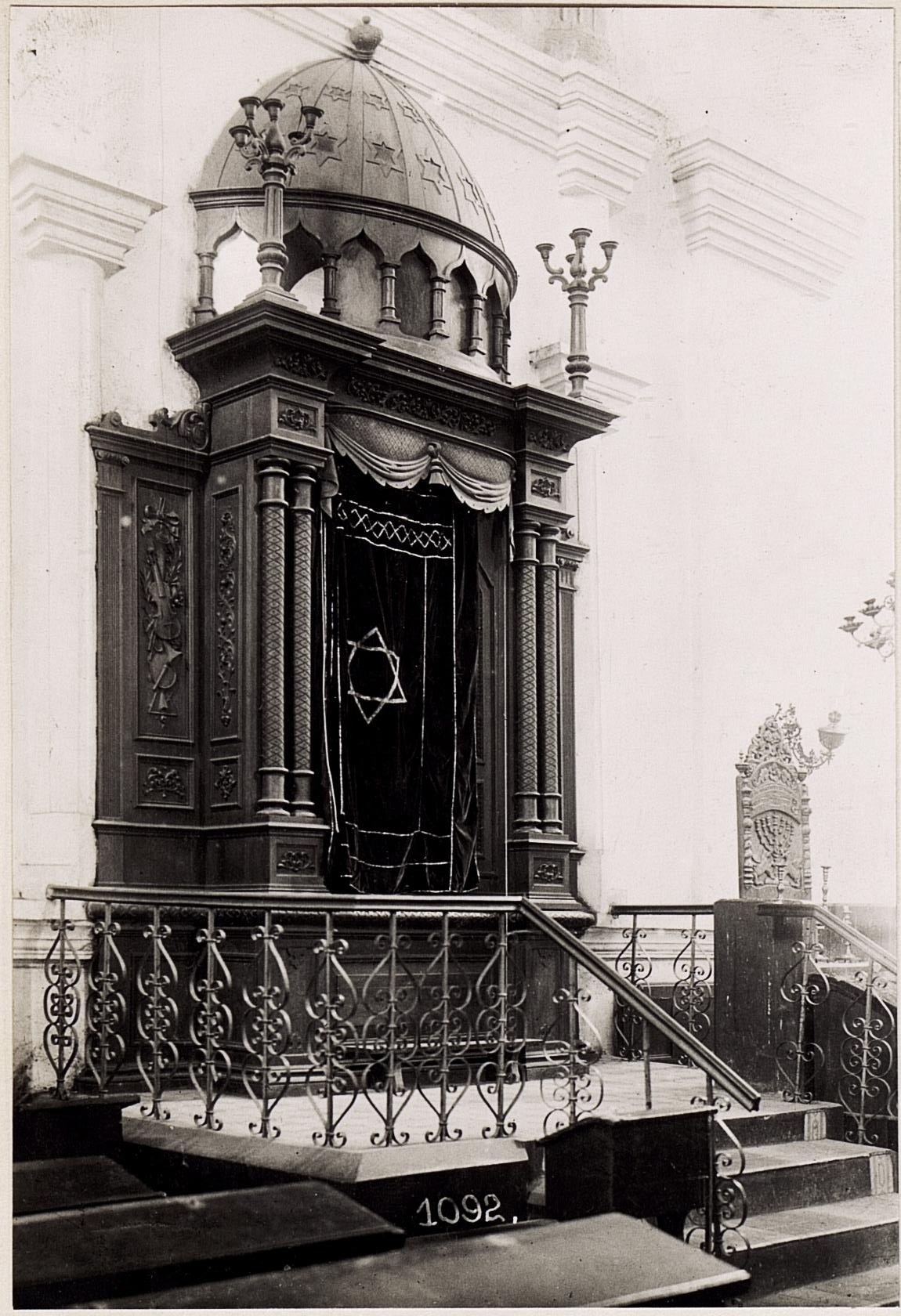 Black and white photograph of a Jewish synagogue in New York City featuring stairs, railings, pillars, a door, and a wall.