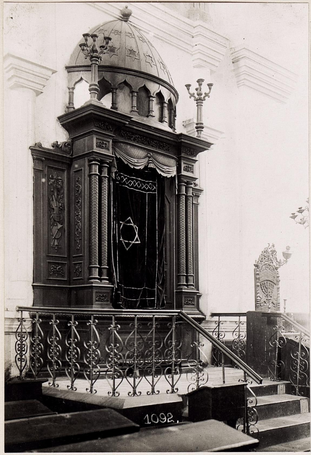Black and white photograph of a Jewish synagogue in New York City featuring stairs, railings, pillars, a door, and a wall.