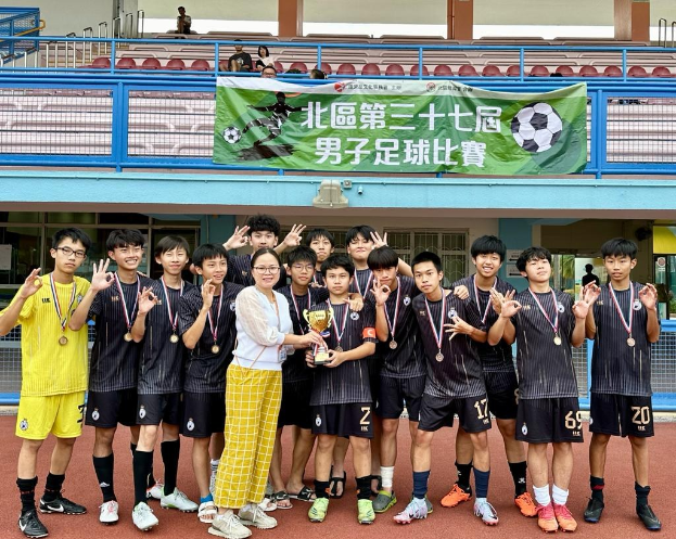 Group of young men in soccer uniforms standing on a field holding a trophy and wearing medals, with a banner for the "Yokohama U-16 Boys Soccer Team" in the background.